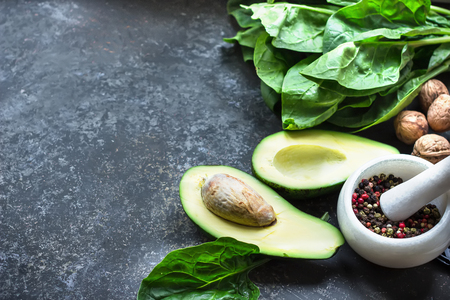 Avocado, spices,walnuts and spinach on grey stone background. Clean food concept. Selective focus, place for text.の写真素材