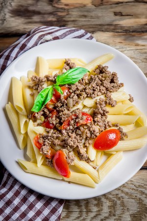 Pasta with tomatoes and meat on wooden rustic background. Top view.の写真素材