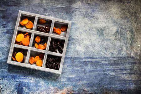 Chocolate sweets with dried fruits and in wooden box. Blue concrete background. place for text.