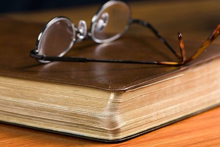 A pair of glasses lays on top of a well read bibleの写真素材