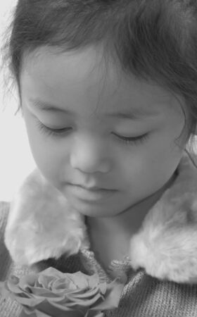 A young girl is lost in thought as she stares at a red rose.の写真素材