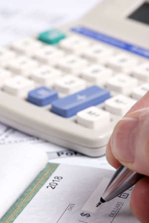 A person fills out a check... paying the bills.の写真素材