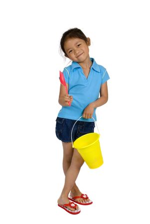 A young girl is ready for the beach with her bucket and shovel. Isolated on whiteの写真素材