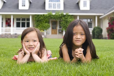 Two young asian girls laying in the grassの写真素材