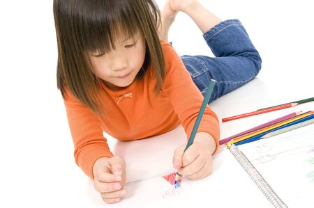 A young asian girl drawing a picture. On whiteの写真素材