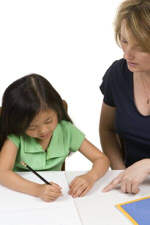 A young girl learns to write with the help of a teacher.の写真素材