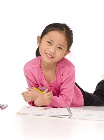 A young asian girl drawing a picture. On whiteの写真素材