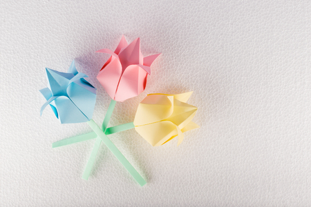 Three origami flowers on white textured backgroundの写真素材