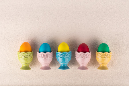 Ceramic egg-cups with colorful painted eggs arranged in a row