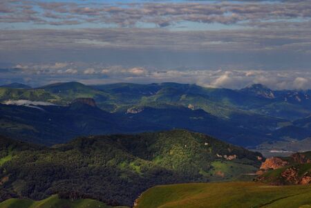 The view of hills illuminated by sun and covered by cloudsの写真素材