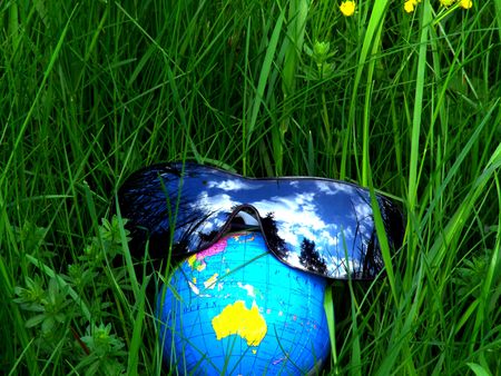 Globe with sunglasses in a meadowの写真素材