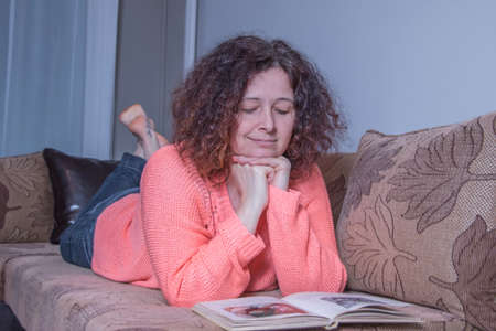 Happy woman lying on the bed and reading a book