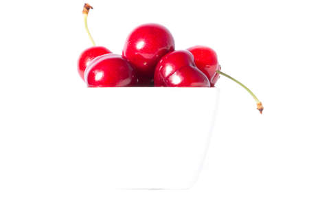 Ripe berries of sweet cherry in a white cup  on white backgroundの写真素材