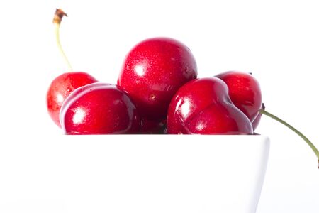 Ripe berries of sweet cherry in a white cup  on white backgroundの写真素材