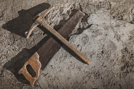 Old weathered grunge pickax and saw on cement floor with copy-spaceの写真素材