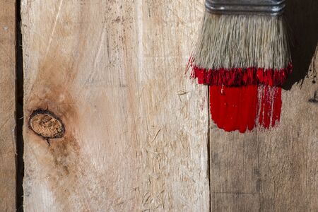 Closeup of pine plank being painted in a red colour, with copy spaceの写真素材