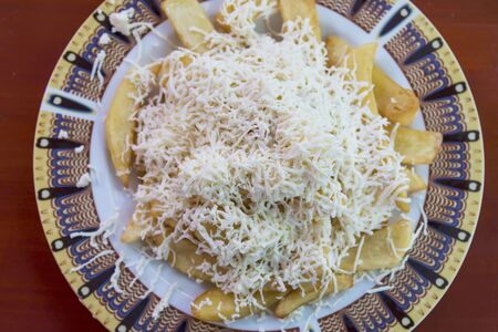 Dish with fried potatoes and white cheese on the red tableの写真素材