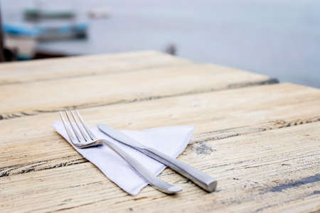 Empty Set In Restaurant. Fork, Knife and Napkin on White Wooden Table.の写真素材