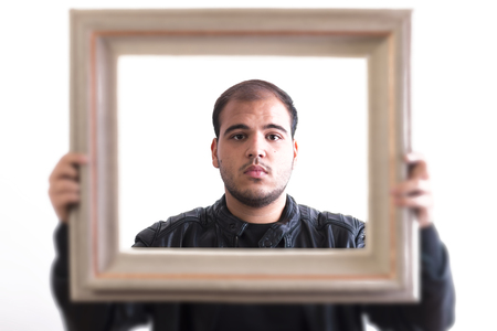 Young Man Looking Through Picture Frame Isolated On White Backgroundの写真素材