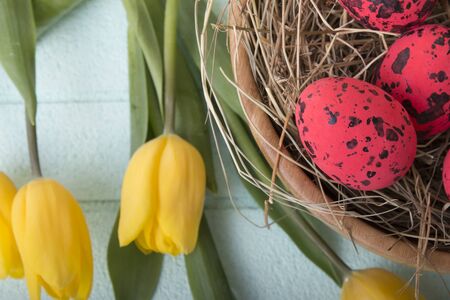 Easter background with red eggs and yellow tulips over blue backgroundの写真素材