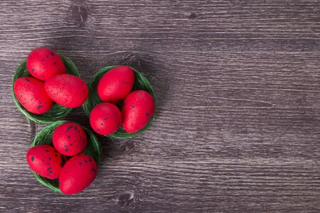 Red Easter eggs on green nest on a wooden tableの写真素材