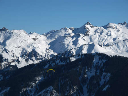 Snow covered mountains and paragliderの写真素材