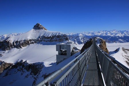 Winter scene on the Glacier des Diablerets. Mount Oldenhorn. Suspension bridge connecting two mountain peaks. Summit station of a cable car.のeditorial素材