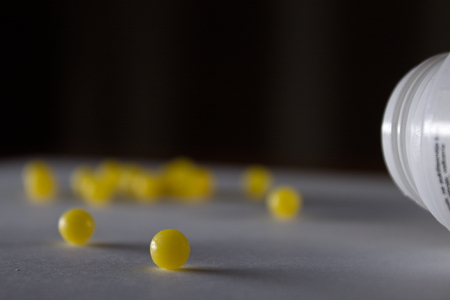 Soft focus close up shot of a single yeallow pill while many other are blured in the backgroundの写真素材
