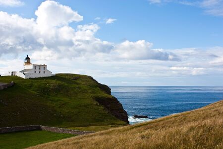 Tipical panorama of Scotland, with a lighthouse and blue skyの写真素材