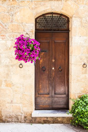 Pienza, Tuscany region, Italy. Old door made of wood with flowersの写真素材