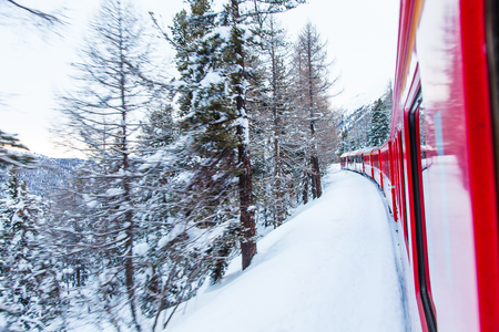 The famous Bernina red train, Unesco monument, in the middle of a winter stormのeditorial素材