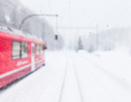 The famous Bernina red train, Unesco monument, in the middle of a winter stormの写真素材