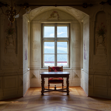 A solitaire chair and table in an ampty room of Castle Savoia, building in typical Walsen architectural style.のeditorial素材
