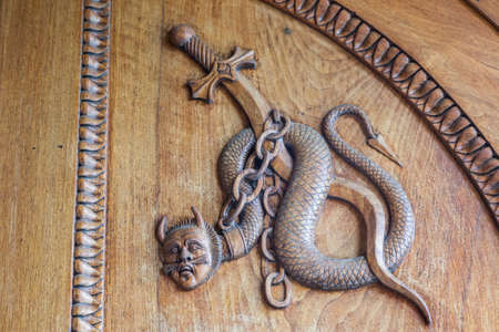 Devil snake symbol. Fantasy magic creature on an old door, 12th Century Abbey, Italy.