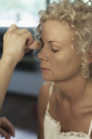 Beautician creating wedding makeup for a young womanの写真素材