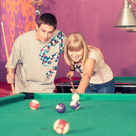 Young people playing billiards in the club