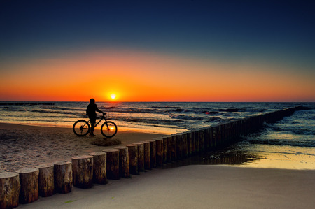 Woman with bicycles on the Baltic Sea at sunsetの写真素材