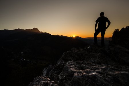 Hiker on a mountain top at sunset. Woman admiring mountain landscape in High Tatra Mountains, Poland.の写真素材