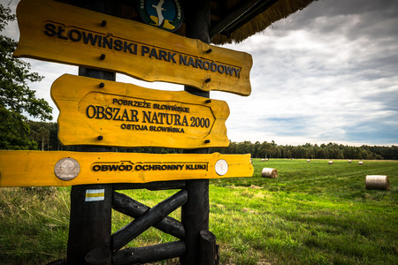 Leba,Poland-September 16,2015:sign on wooden pole marking entrance to Slowinski National Parkのeditorial素材