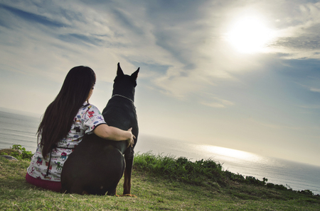 A woman and her dog watching the sunsetの写真素材