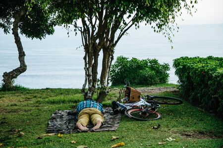 Man sleeping on the lawn with his bicycleの写真素材
