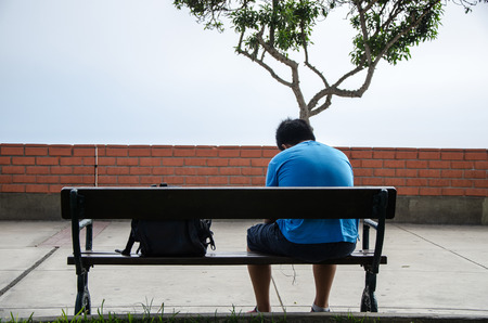Child sitting on his back on a bench in the parkの写真素材
