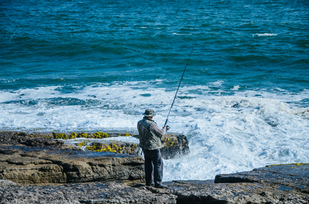 Fisherman on the seashore with his fishing rodの写真素材