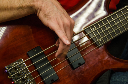 Closeup of photo of electric bass guitar player playing with hands