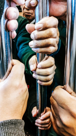 Closeup, people hands holding handrail inside the train.の写真素材