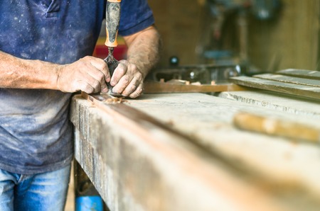 Professional carpenter at work, he is carving wood using a woodworking tool, carpentry and...