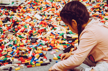 Little girl playing with many plastic building bricks parts. Educational toy for childrenの写真素材
