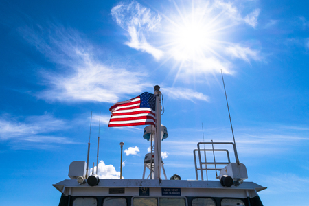 Majestic United States flag with blue sky backgroundの写真素材