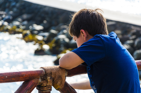 A boy looking at the sea with his back to the camera. Child looking at the sea on the beachの写真素材