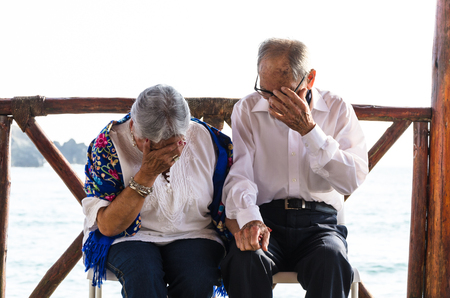 Elderly couple looking at each other laughing. Elderly couple with the sea background.の写真素材